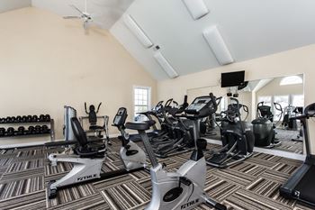 a gym with various cardio machines and dumbbells at Brickshire Apartments, Merrillville, IN, 46410